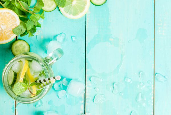 نوشیدنی با طراوت تابستانی - سم زدایی دم نعنا خیار و لیمو روی میز چوبی آبی روشن نور خورشید روشن کپی sp نمای بالا