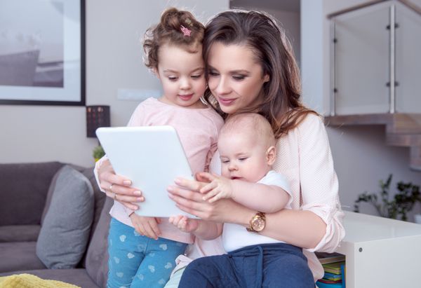 مادر جوان در حال گشت و گذار در اینترنت با فرزندان کوچکش