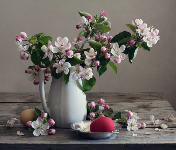 طبیعت بی جان با گل های سیب و تخم مرغ روی میز چوبی