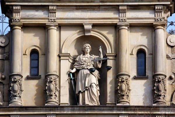 Justitia بانوی عدالت ایستاده با مقیاس و شمشیر بر روی نمای ساختمان عدالت جنایی در هامبورگ آلمان