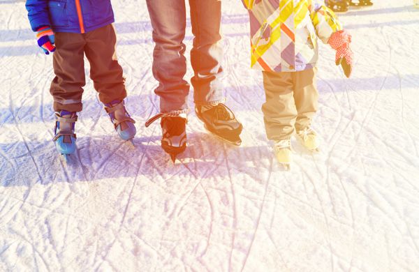 پدر با بچه های اسکیت در زمستان ورزش زمستانی خانوادگی