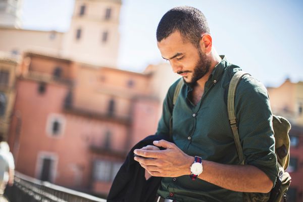 مسافر جوان ریشو با استفاده از گوشی هوشمند خود