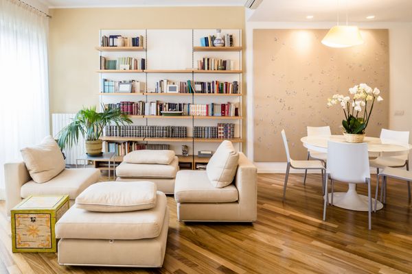 soggiorno in appartamento con tavolo rotondo libreria a muro e parket curato e pulito in stile classico