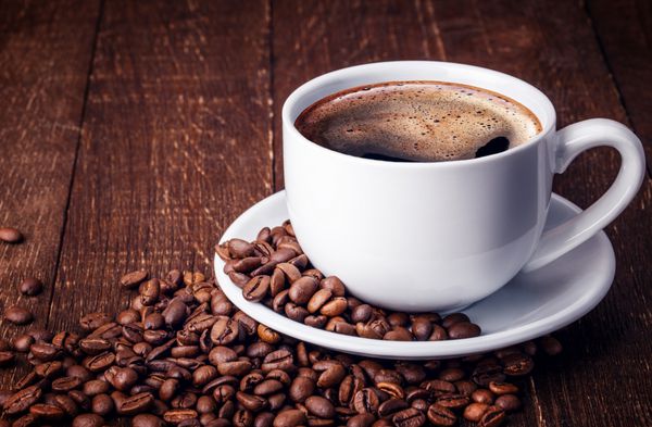 فنجان قهوه و نعلبکی روی میز چوبی