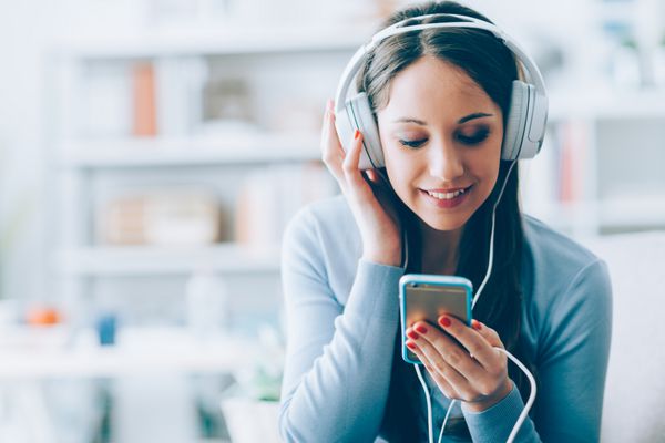 دختری که با گوشی هوشمندش به موسیقی گوش می دهد