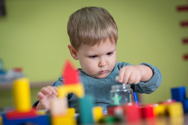 بچه در حال بازی با اسباب بازی ها در مهد کودک است