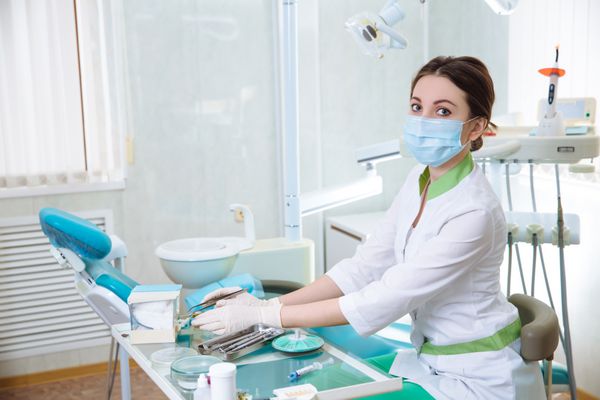 زن دندانپزشک با ابزار پزشکی در مطب دندانپزشکی در حال انجام مراحل
