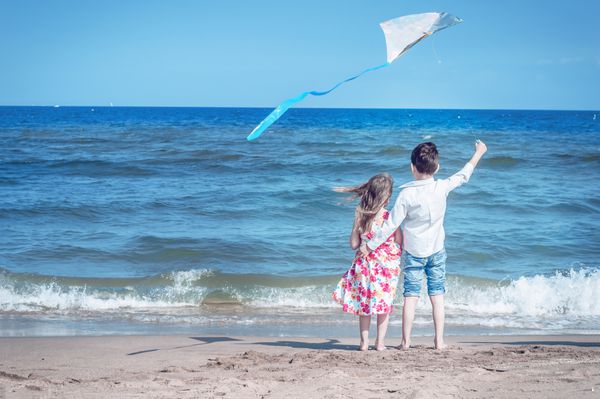 دختر و پسر در ساحل با بادبادک آزادی کودکی بی خیال