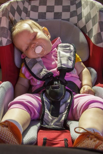 دختر بچه تازه متولد شده کوچک روی صندلی ماشین استراحت می کند