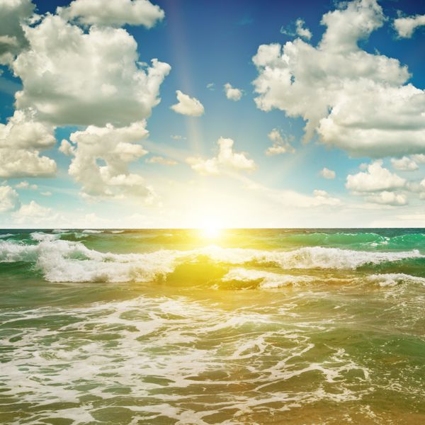 اقیانوس ساحل شنی آسمان آبی و طلوع خورشید