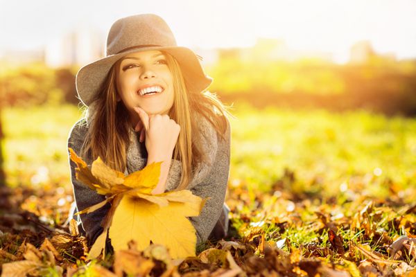 زن جوان شاد در پارک در روز آفتابی پاییزی