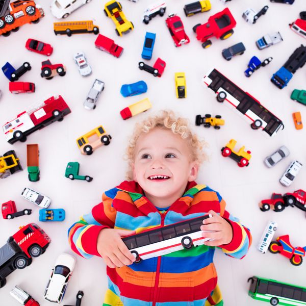 پسر بچه در حال بازی با ماشین های اسباب بازی