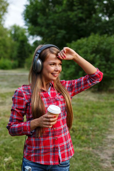 دختر در حال گوش دادن به موسیقی و نوشیدن قهوه