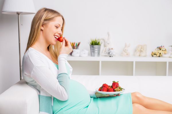 زن باردار در حال خوردن توت فرنگی