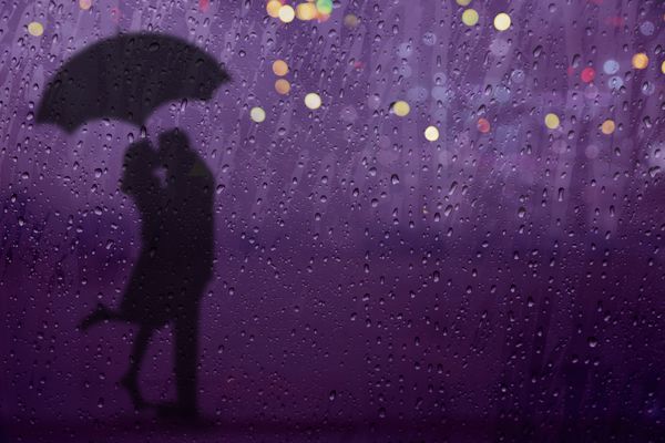 عاشق تار در حال بوسیدن زیر باران با چتر و نور شهر در خیابان در شب از پنجره شیشه ای دیدن تمرکز انتخابی روی قطره