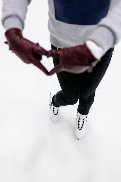 نمای نزدیک از دختر نماد قلب انتزاعی را با دستکش های چرمی روی پیست اسکیت نشان می دهد مفهوم عشق به اسکیت ورزش های زمستانی
