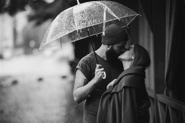 پسر و دختر در حال بوسیدن زیر چتر
