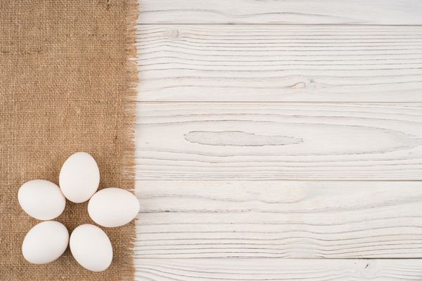 تخم مرغ روی میز چوبی قدیمی سفید