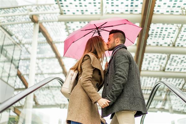 دو عاشق در حال بوسیدن یکدیگر در پله برقی مرکز خرید