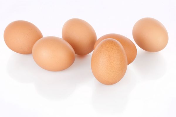نیم دوجین تخم مرغ قهوه ای جدا شده در پس زمینه سفید