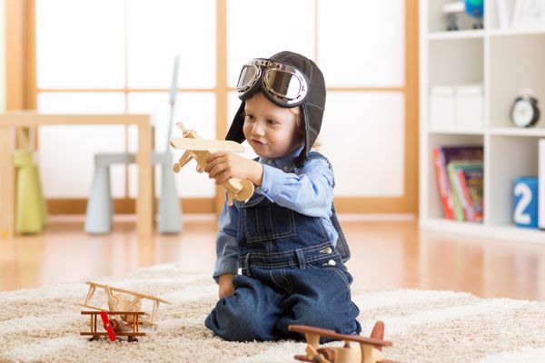 کودک شاد با اسباب بازی های هواپیما بازی می کند و آرزو دارد خلبان شود