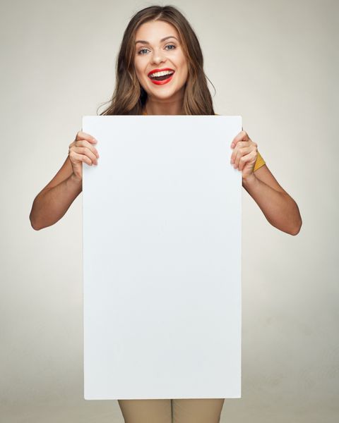 زن جوان خندان تخته بزرگ سفید را برای علامت تبلیغاتی نشان می دهد