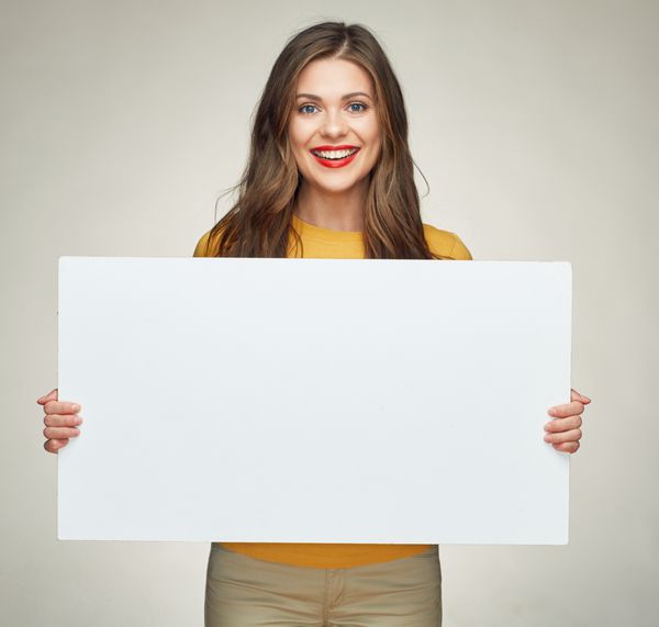 زن جوان خندان تخته بزرگ سفید را برای علامت تبلیغاتی نشان می دهد