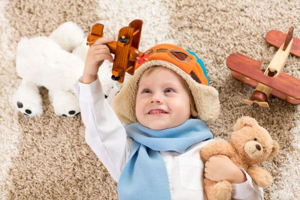 پسر بچه خوشحال در حال بازی با هواپیمای اسباب بازی