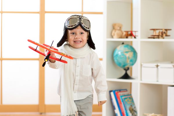 پسر بچه شاد با هواپیمای اسباب بازی بازی می کند و آرزوی خلبان شدن را دارد