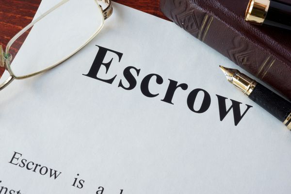 کاغذ با کلمه Escrow و لیوان روی میز