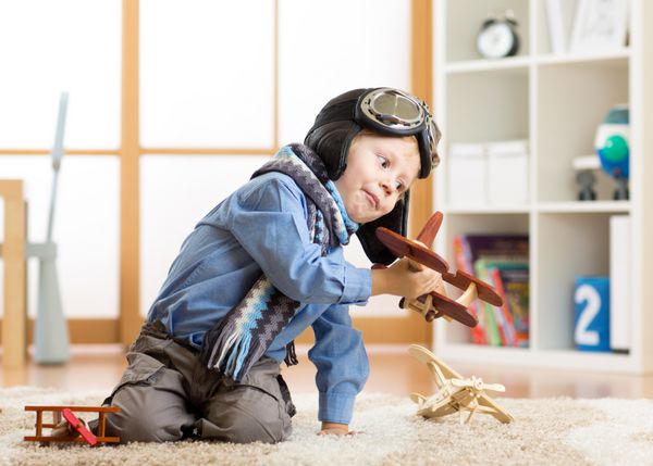 مفهوم رویاها و تخیل کودکان پسر کوچک شایان ستایش در حال بازی با هواپیمای چوبی