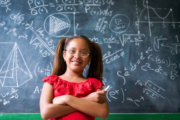 پرتره دختر شاد در حال حل مسئله پیچیده ریاضی روی تخته سیاه