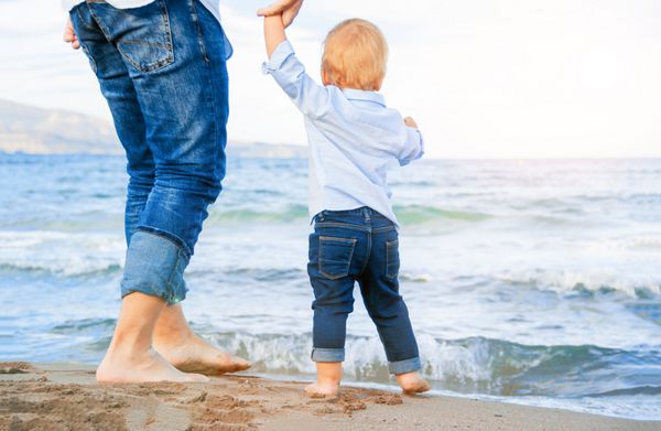 پای برهنه کودک و بزرگسال روی دریا مفهوم تعطیلات خوشحال