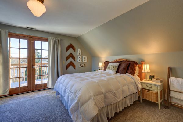 اتاق خواب آرام با سقف شیبدار و درهایی به عرشه زیبا