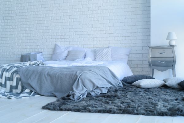 فضای داخلی اتاق خواب با دیوار آجری با تخت و میزهای کنار تخت