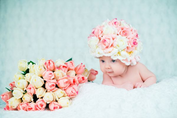 نوزاد دختری با کلاه رز لبخند می زند پرتره در پس زمینه سفید