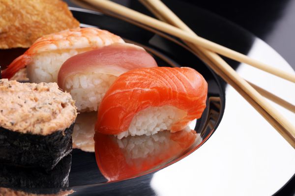 کلوزآپ ست سوشی ساشیمی با چاپستیک و سویا - رول سوشی با ماهی قزل آلا و رول سوشی با مارماهی دودی فوکوس انتخابی - ماکی و نیگیری خوشمزه