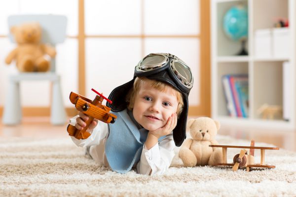 پرتره پسر بچه در حال بازی با هواپیمای چوبی