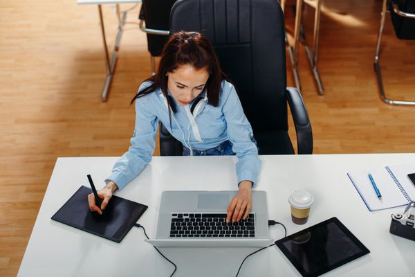 زن جوان در حال طراحی روی لپ تاپ در دفتر