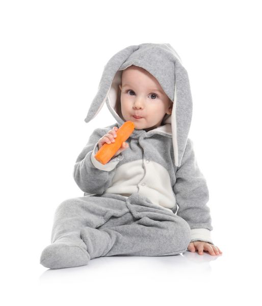 کودک کوچولوی ناز در لباس اسم حیوان دست اموز با هویج در پس زمینه سفید