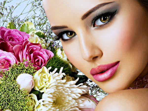 زن زیبا با دسته گلهای تازه در صورت