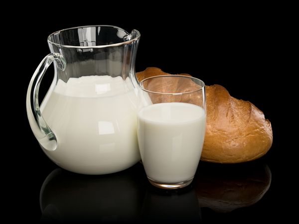ظروف شیشه ای پر از شیر و یک نان بلند سفید