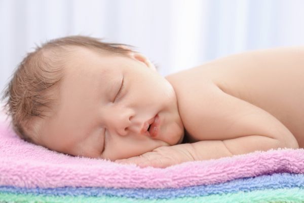 کودک کوچولوی ناز که روی حوله در خانه می خوابد نزدیک