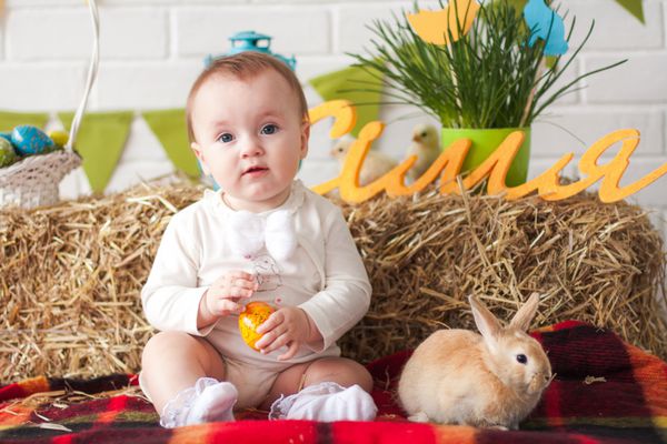 نوزاد کوچولوی بامزه ای که در روز عید پاک تخم در دست دارد