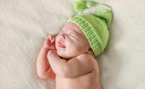 نوزاد تازه متولد شده خندان در کلاه سبز خوابیده