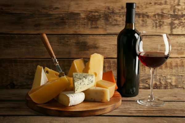شراب قرمز و تخته پنیر در پس زمینه چوبی