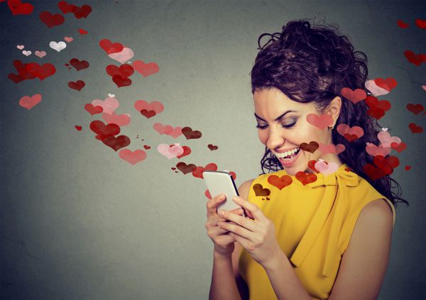 زن شاد در حال ارسال پیامک عاشقانه در تلفن همراه