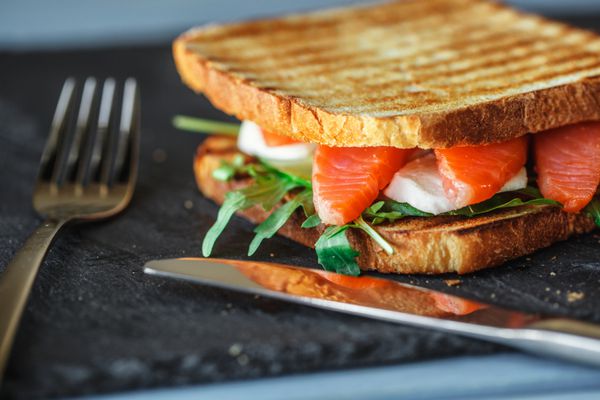 ساندویچ خوشمزه با ماهی قرمز آرگولا خیار پنیر موزارلا آب گوجه فرنگی و گیلاس