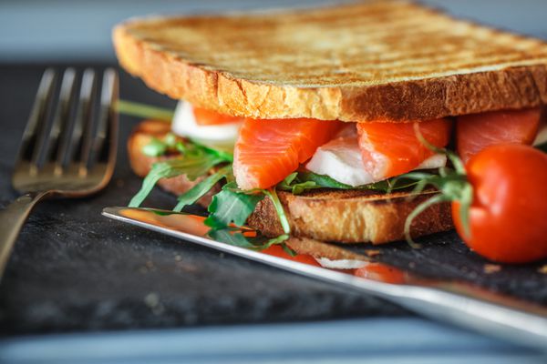 ساندویچ خوشمزه با ماهی قرمز آرگولا خیار پنیر موزارلا آب گوجه فرنگی و گیلاس