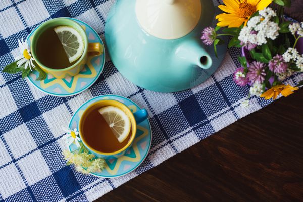 فنجان چای گیاهی با بابونه و برگ نعناع روی زمینه چوبی